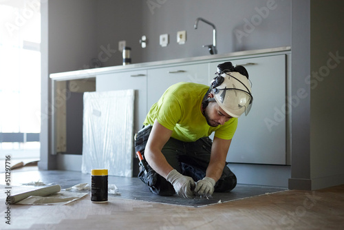 Worker installing floor in kitchen photo