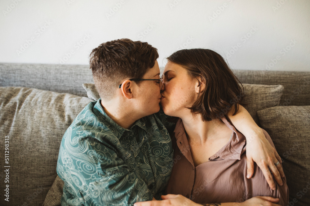 Female couple kissing on sofa Female couple kissing on sofa