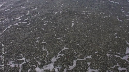 Sea tide on a pebble shore. Waves with white foam on a pebble beach. Nature concept, vacation, background