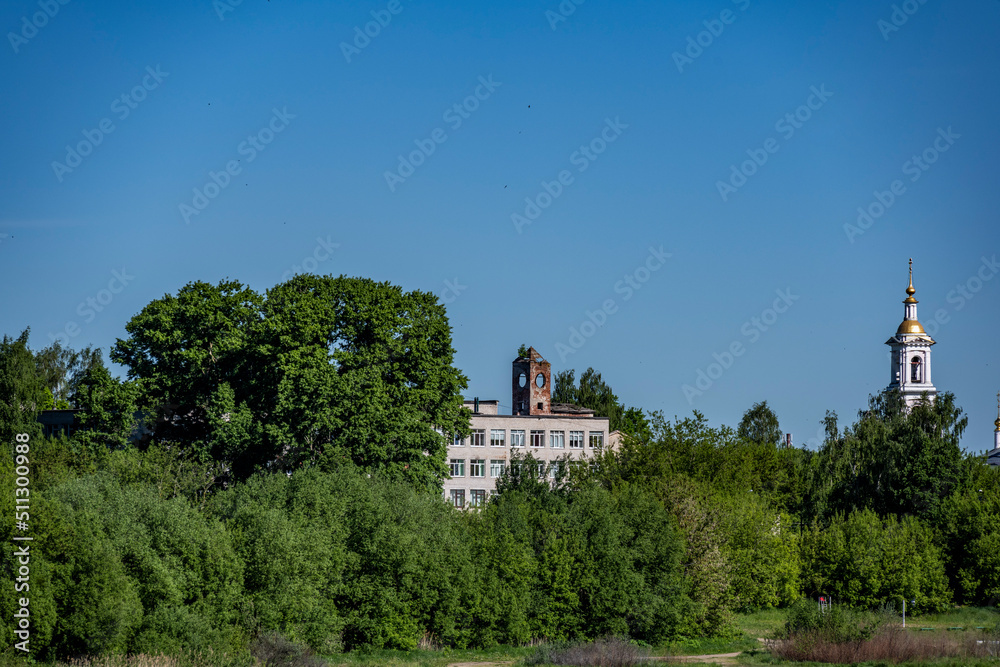 summer landscape with ancient churches against the backdrop of a forest and a river on a sunny day