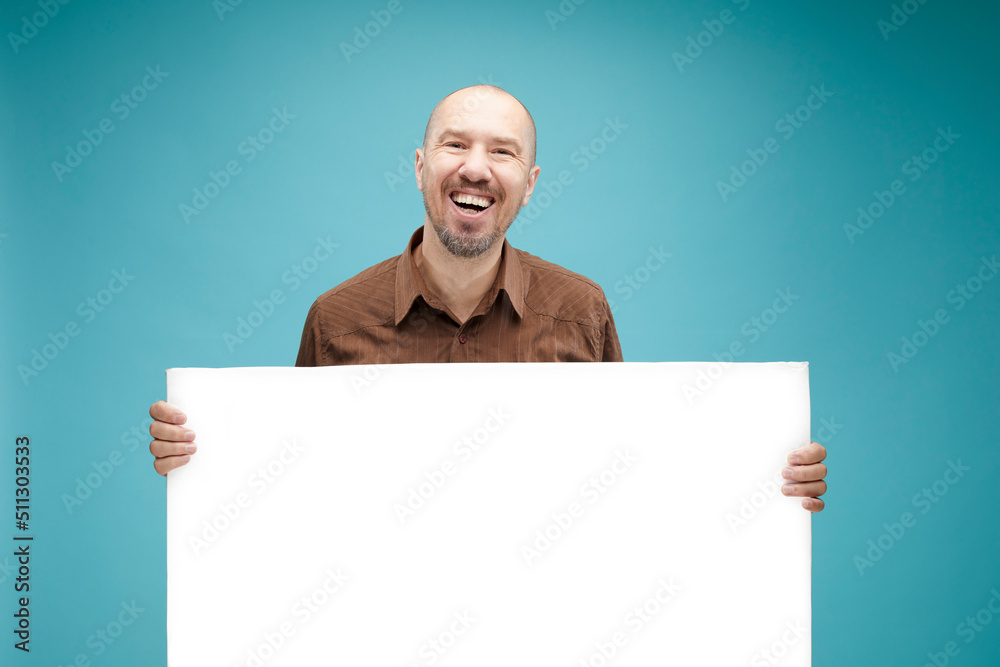  A Bald man with emotion face holding  white board in his hands to fill your text. Isolated on blue background.
