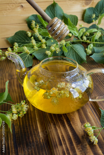 Tea with linden flower in the glass teapotn on the wooden background. Closeup. Location vertical. photo