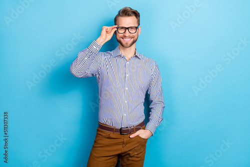 Photo of cheerful man hand touch glasses toothy smile look camera isolated on blue color background