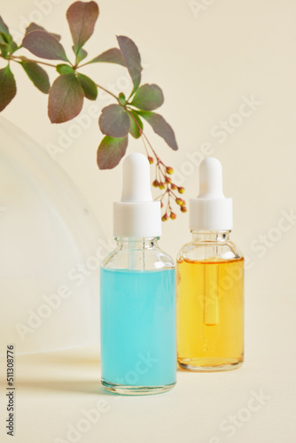 blue and orange serums in transparent dropper bottles on a beige background, natural cosmetics and skin care