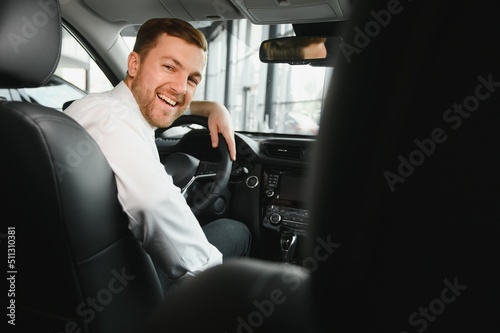 Canvas-taulu Taxi driver smiling while turning over to the backseat looking talking with clients