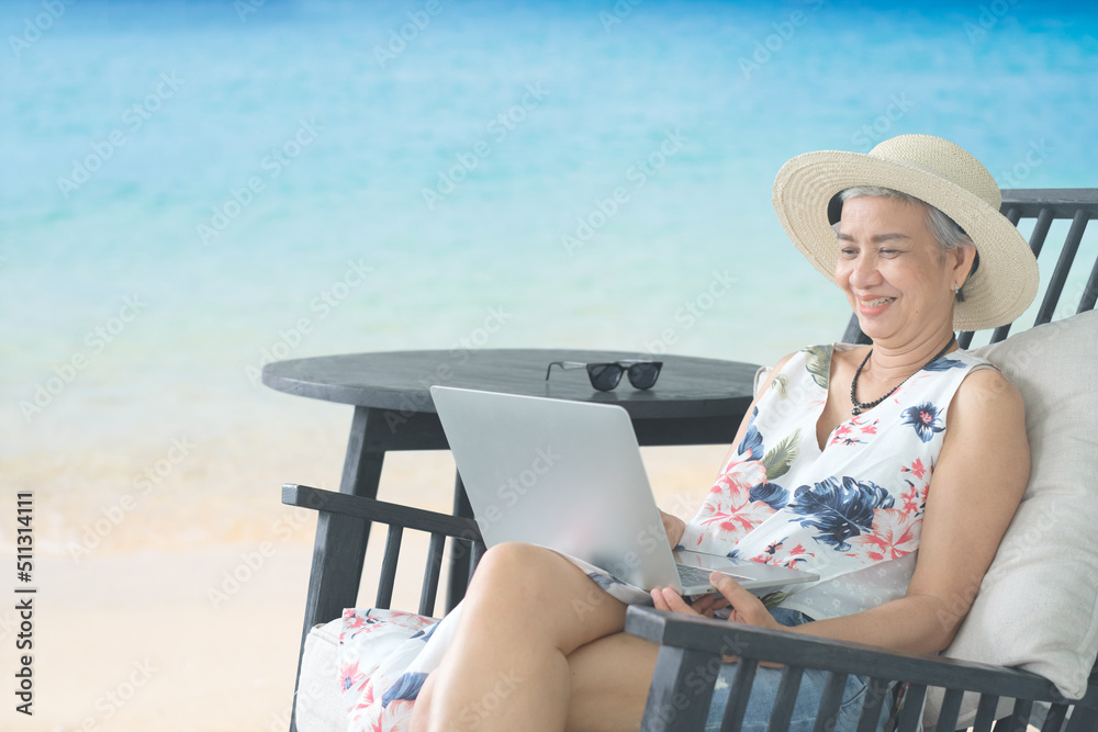 Work from anywhere concept. woman, female freelancer in straw hat working on laptop, smile and happy work success while sitting on the tropical sandy beach.