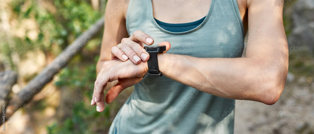 Partial of young sportswoman using fitness tracker