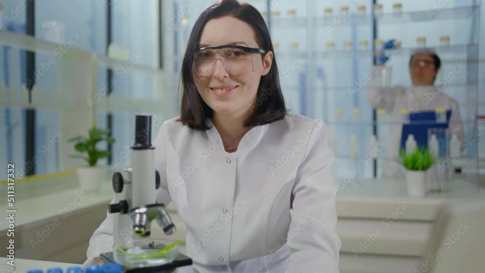 close-up modern laboratory plant research portrait of a woman scientist microscope looks into the camera and smiles close-up modern laboratory plant research portrait of a woman scientist microscope looks into the camera and smiles
