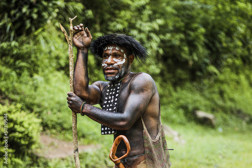 Portrait of Dani Tribe man wearing koteka, traditional clothes of Papua. Dani tribe men ready to hunt animal prey in the jungle.  photo
