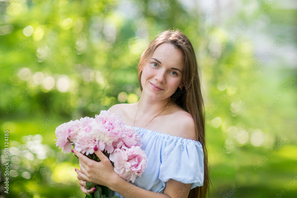 Young woman smiling behind pink peony flower Young woman smiling behind pink peony flower