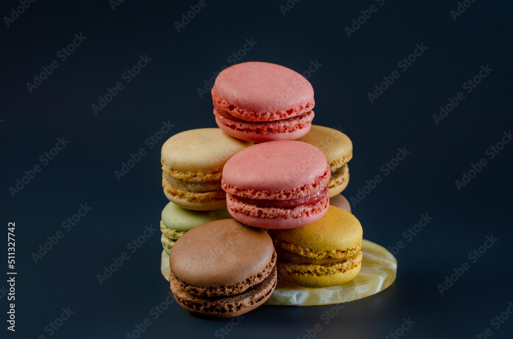 Row of delicious colorful French macaroons of different flavors on black background with copy space. High - quality photo