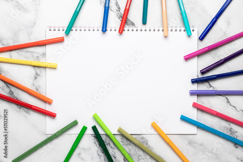 Background with pencils and white blank paper, felt pens frame. Open sketchbook. Mockup, template. Colored markers for drawing on a marble desk. Flat lay composition. Space for text.