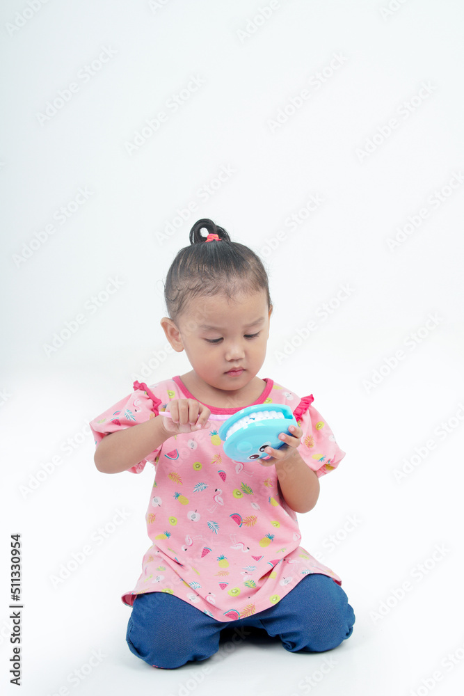 Little girl shows how to properly brush her teeth using the example of a jaw model on white background. Child demonstrates brushing his teeth. Hygiene, prevention and protection of teeth and gum. Little girl shows how to properly brush her teeth using the example of a jaw model on white background. Child demonstrates brushing his teeth. Hygiene, prevention and protection of teeth and gum.