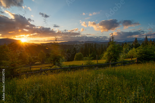 Travel photo of Ukrainian Carpathians. Scenic views of the mountain ranges during sunset, the sky with clouds and the settlements of local residents.