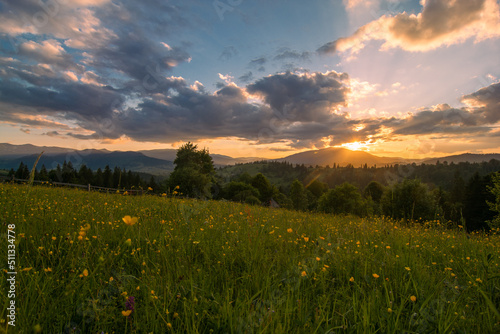Travel photo of Ukrainian Carpathians. Scenic views of the mountain ranges during sunset, the sky with clouds and the settlements of local residents.