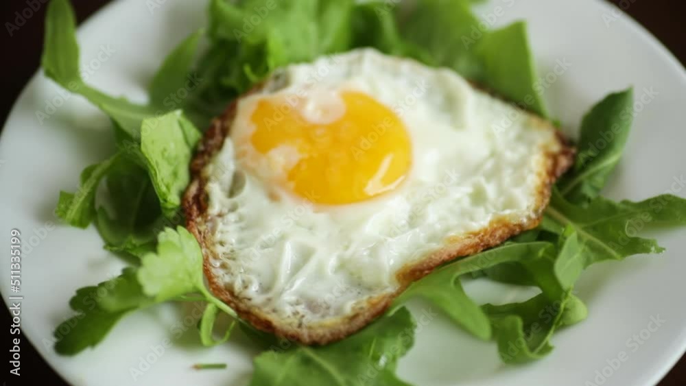 one fried egg with arugula and lettuce in a plate on a wooden table one fried egg with arugula and lettuce in a plate on a wooden table