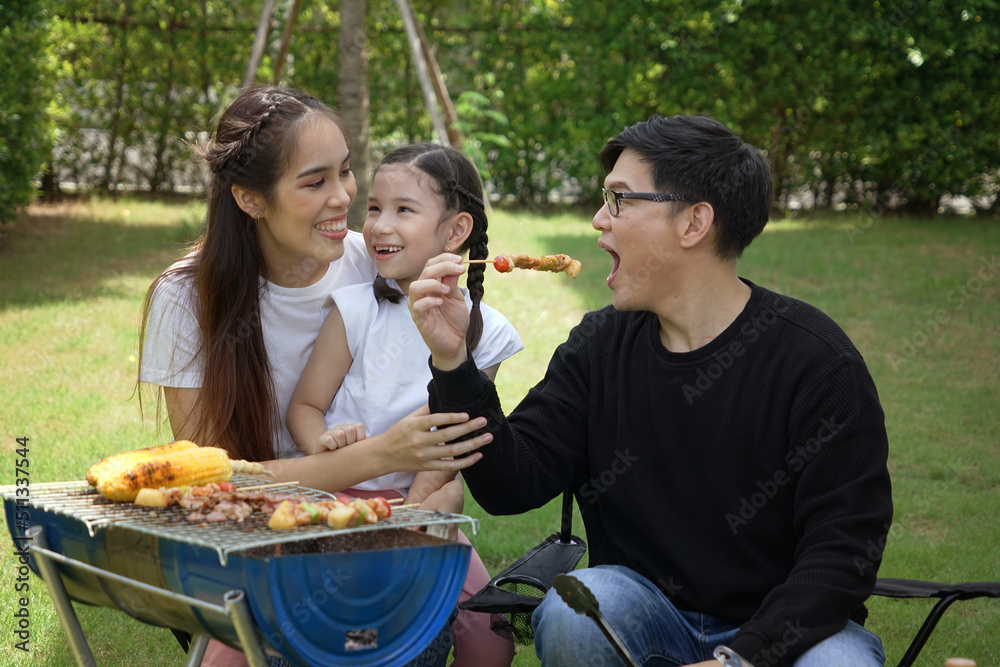 Dad grills a barbecue with mom and son, daughter picnics on vacation together as a family having