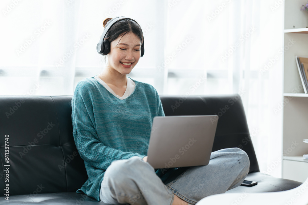 Beautiful smiling young woman in headphones chatting via laptop computer video call at home Beautiful smiling young woman in headphones chatting via laptop computer video call at home