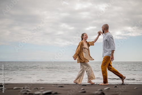 Young loving couple dancing and holding hands on a beach