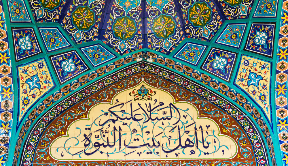 Arabic calligraphy on mosque tiled wall. Translation: Peace be upon you, O people of the House of Prophethood
