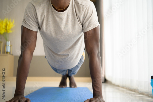 Young African man doing yoga exercise in the living room of his homewith the pleasure of relaxing with light sports In the morning atmosphere of the day. photo