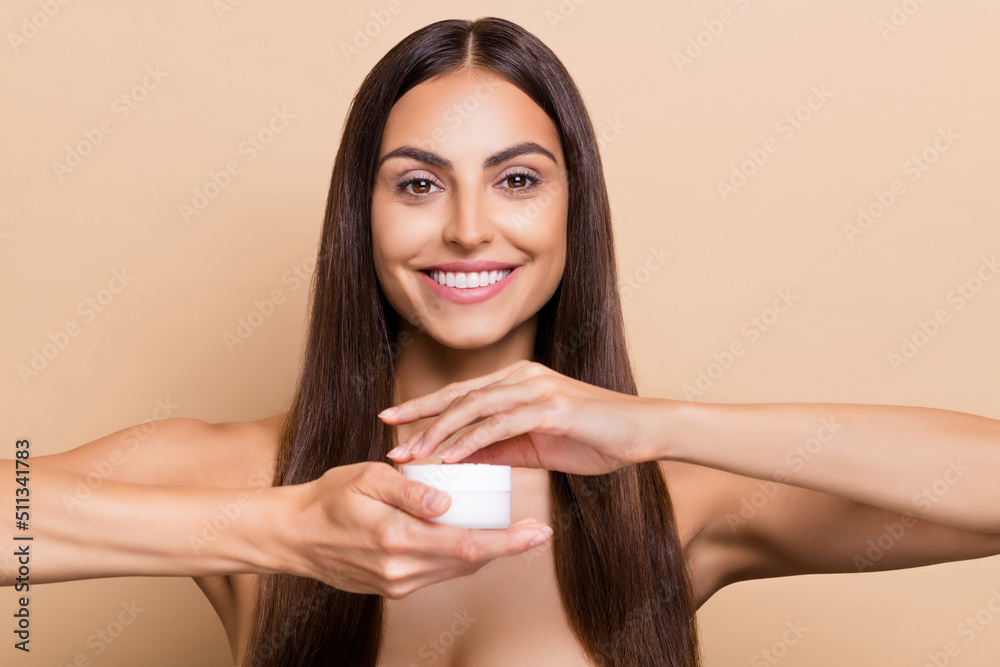 Portrait of attractive cheery girl holding daily cream perfection vitamin isolated over beige pastel color background Portrait of attractive cheery girl holding daily cream perfection vitamin isolated over beige pastel color background