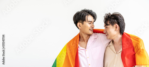 Guys spend time together at home, Portrait of Happy Asian gay couple embracing and showing their love under lgbt colorful rainbow flag. LGBT and love concept.