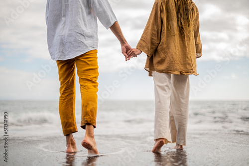 Young loving couple shown from behind holding hands on a beach
