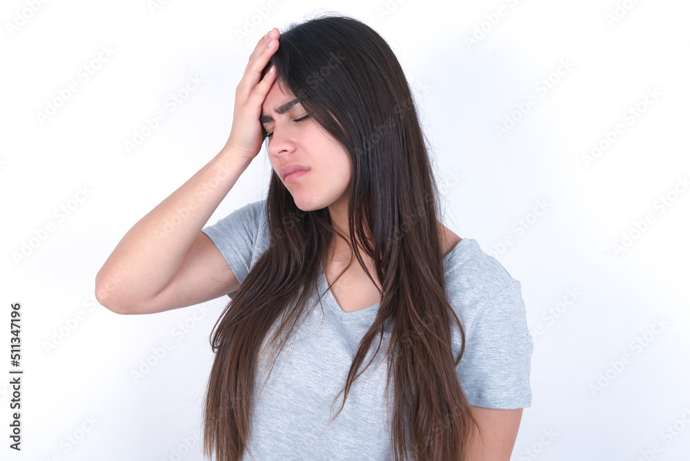 A very upset and lonely young beautiful brunette woman wearing grey t-shirt over white wall crying,