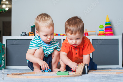 Two children boy play together with toys in interior of children's room..