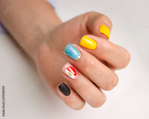 The hands of a young woman with a manicure. Nails covered with gel polish with a bright multicolored design