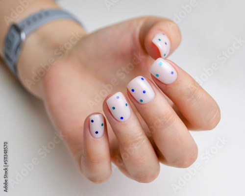 The hands of a young woman with a manicure. Nails covered with gel polish of a milky shade