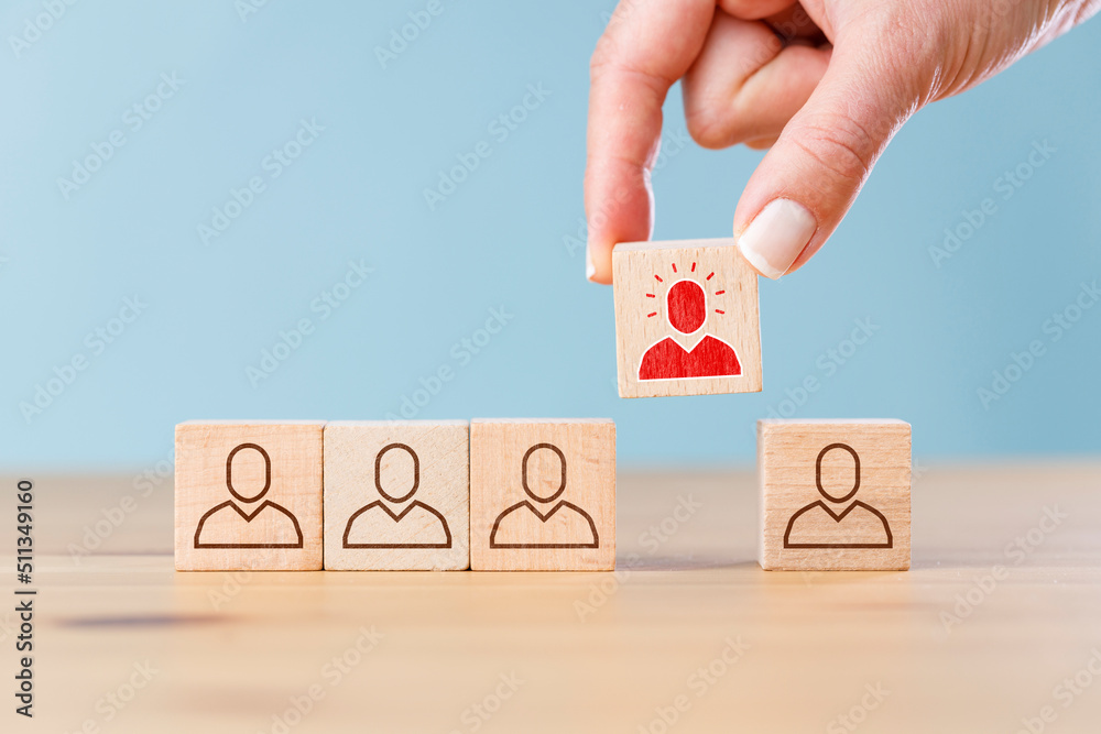 Person icon on wooden cube with hand picked different from the crowd Person icon on wooden cube with hand picked different from the crowd
