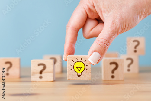 Bilde på lerret Woman hand picked wooden cube block with light bulb icon and question mark symbol