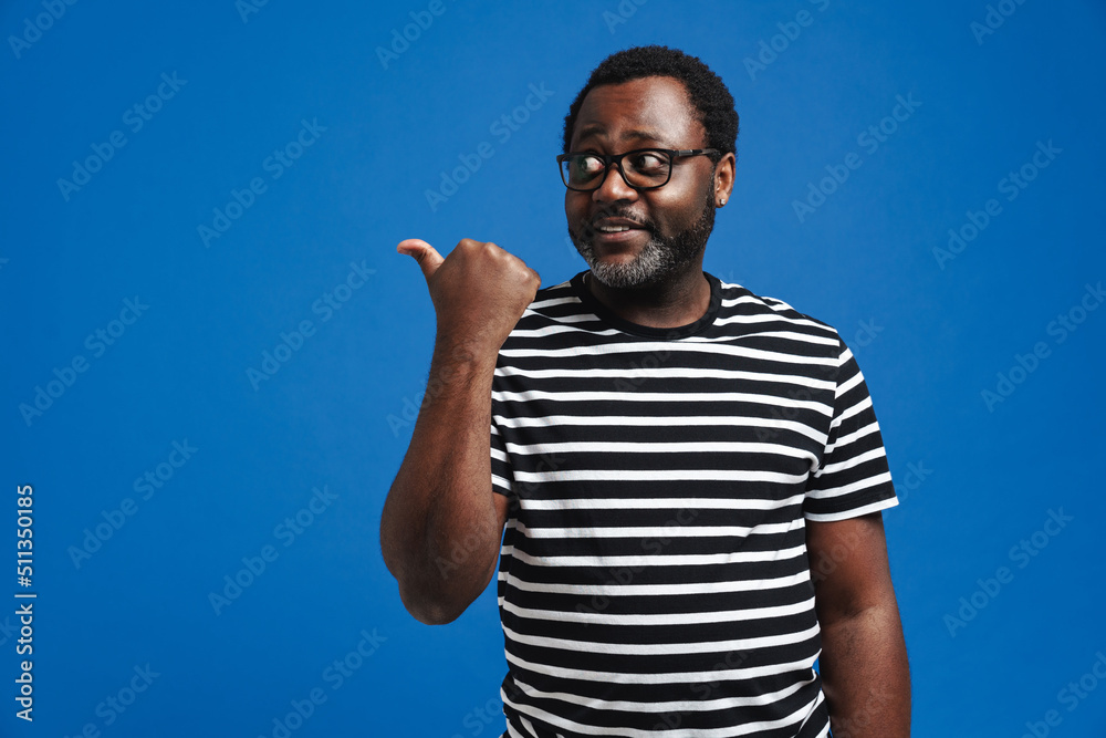 African american man wearing eyeglasses smiling and gesturing aside African american man wearing eyeglasses smiling and gesturing aside