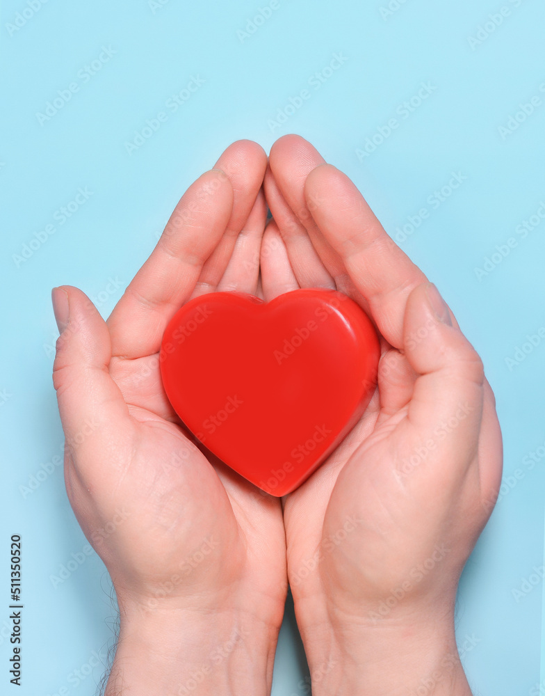 Red heart in man's hands isolated on blue background. Healthcare and hospital medical concept. Symbolic of Valentine day.Top view with space for text.