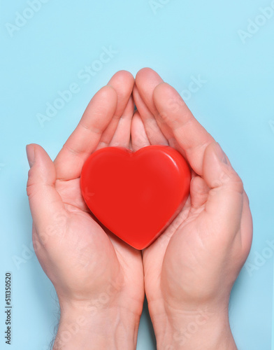 Red heart in man s hands isolated on blue background. Healthcare and hospital medical concept. Symbolic of Valentine day.Top view with space for text.