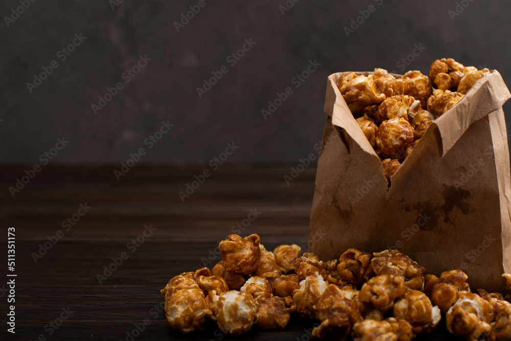 Caramelized popcorn in paper bag on wooden kitchen table