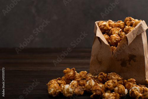 Obraz na płótnie Caramelized popcorn in paper bag on wooden kitchen table w salonie