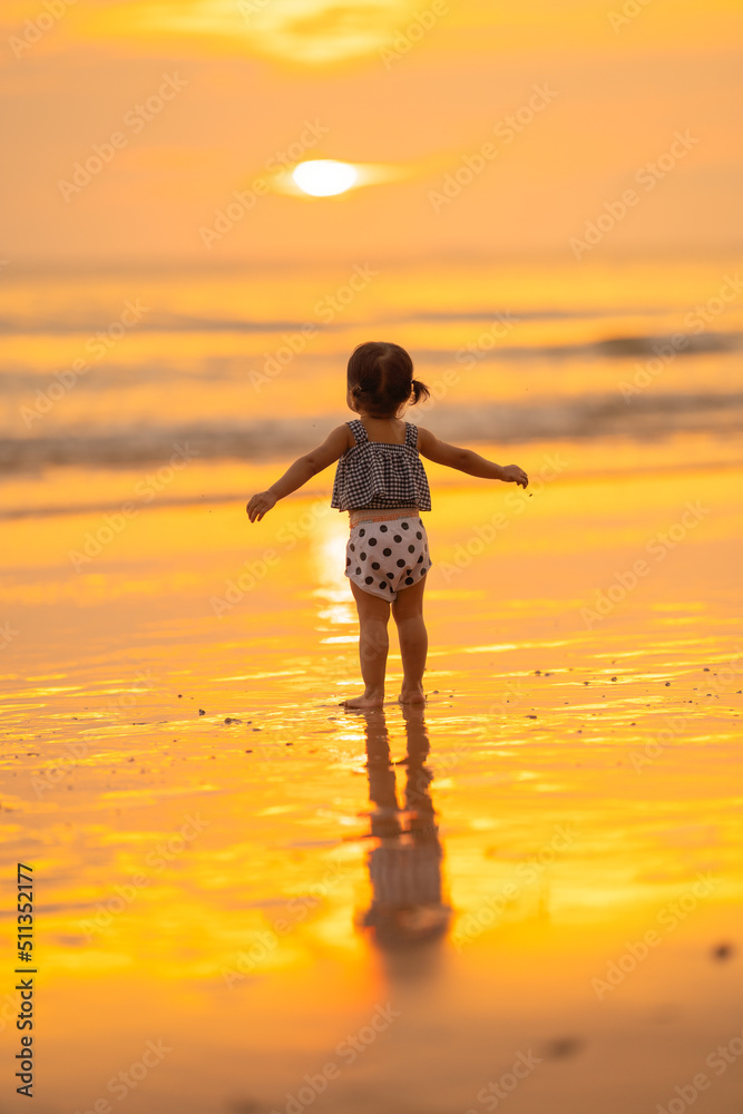 baby girl back view with freedom emotional happy time stand on beach in evening time with beautiful sunset light