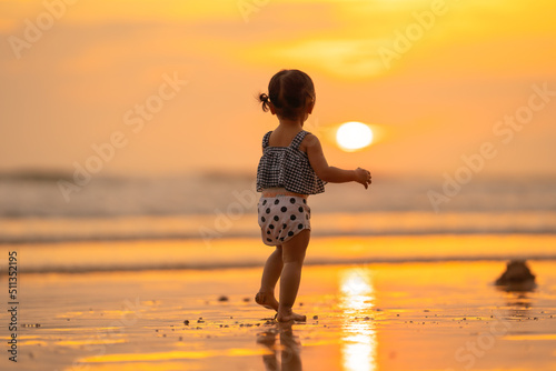 baby girl back view with freedom emotional happy time stand on beach in evening time with beautiful sunset light