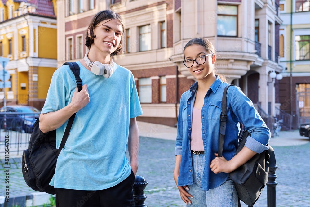 Portrait of teenage young guy and girl students looking at camera, outdoor