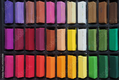 Set of colored pastels laid out in a black box. The concept of classes in creativity, drawing, art. Stationery for teaching children at school. Colored pencils, dry pastel, chalk