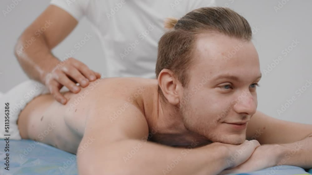 Happy man have a sap day in a spa salon he have a full back relax massage he have a happy face and enjoy the moment while masseur massage his back