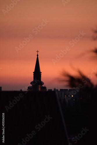 Church tower at the sunset with some rooftop in the front