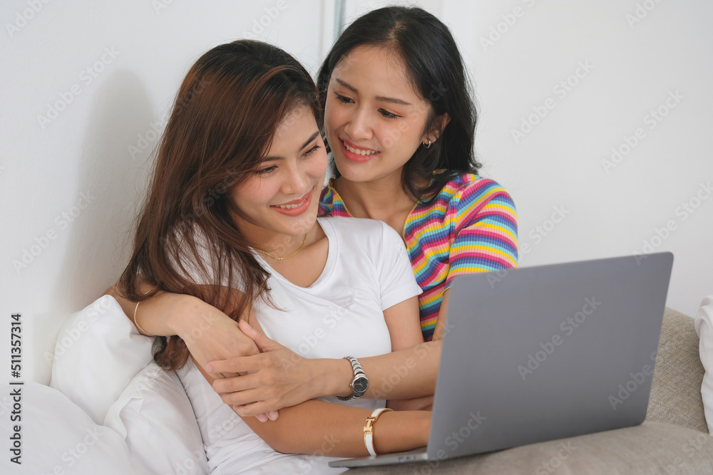 lgbtq lgbt concept homosexuality Two beautiful women happily express their love for each other playing laptop computers in their comfortable homes. lgbtq lgbt concept homosexuality Two beautiful women happily express their love for each other playing laptop computers in their comfortable homes.