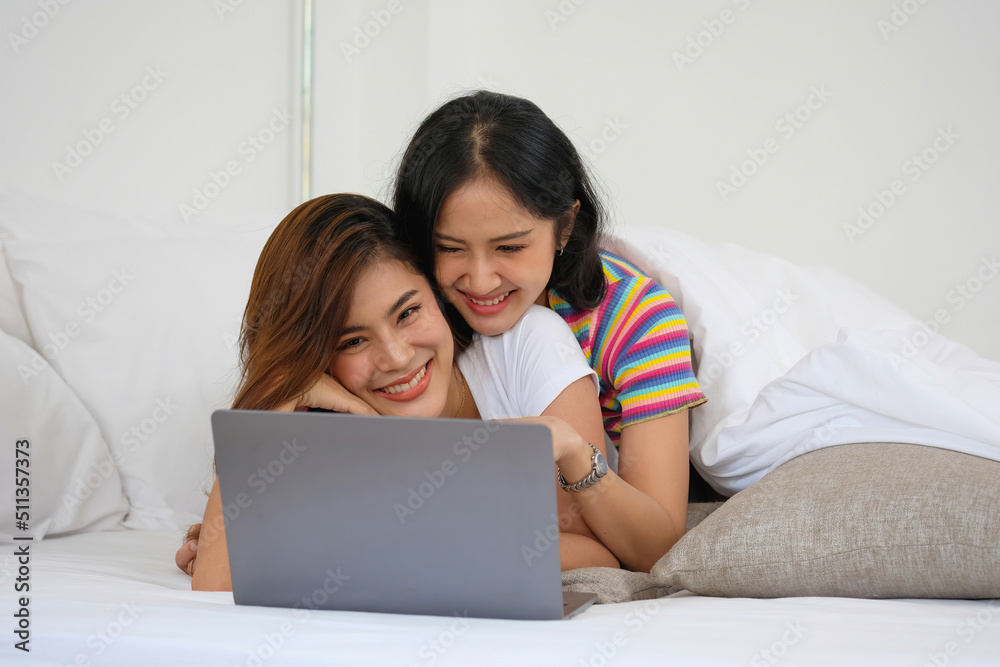 lgbtq lgbt concept homosexuality Two beautiful women happily express their love for each other playing laptop computers in their comfortable homes. lgbtq lgbt concept homosexuality Two beautiful women happily express their love for each other playing laptop computers in their comfortable homes.