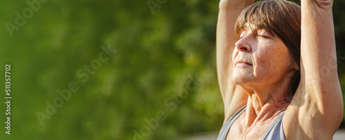 Banner An old slender woman does yoga in the park