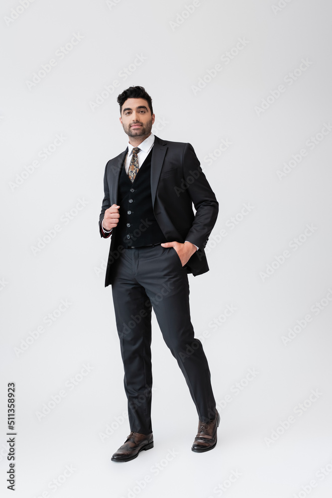 full length of muslim man in formal wear standing with hand in pocket on grey. full length of muslim man in formal wear standing with hand in pocket on grey.