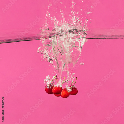 Fresh red cherry fruits water splash. Minimal food concept. Summer bold pink background.